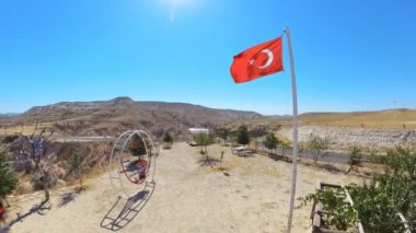 Türkiye 'nin Kapadokya kentindeki Devrent Vadisi Gözcüleri' nde Türk bayrağı taşıyan turist bir kadın. Devrent Valley 'in gerçeküstü manzarasına hayran olmak için büyüleyici bir bakış açısı sunuyor..