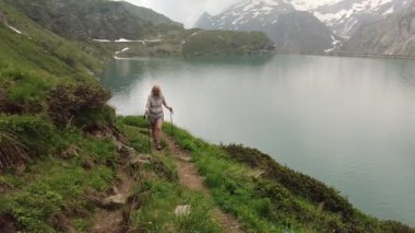 Robiei Gölü 'nün ve barajının önünde yürüyen turist bir kadın. Ticino kantonunun Maggia Vadisi 'ndeki İsviçre rezervuarı. İsviçre 'nin San Carlo şehrinden tramvay istasyonunun tepesinde..