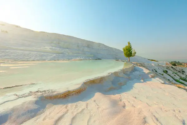 stock image Pamukkale in Turkey reveals its breathtaking thermal pools. Adorned with radiant white terraces, crafted by the mineral-enriched thermal waters cascading down the mountainside.