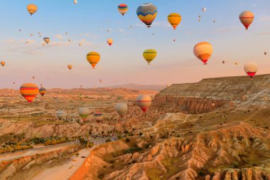 Kapadokya 'da balonlar göğe yükselir. Parlak balonlar giderek azalan güneş ışığını yakalayarak, Türkiye 'nin Kapadokya bölgesindeki Goreme bölgesinde gerçeküstü zirveler üzerine mistik bir parlaklık yansıtıyor..