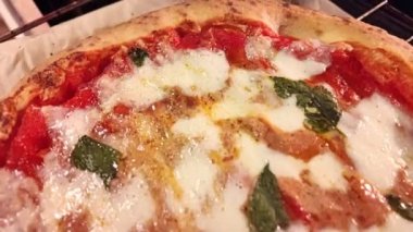 Domates, mozzarella ve fesleğen yapraklı yuvarlak Margherita pizzası. Pizza sosunun kaynama görüntüsünü kapat. Ekstra saf zeytinyağlı İtalyan tarifi.