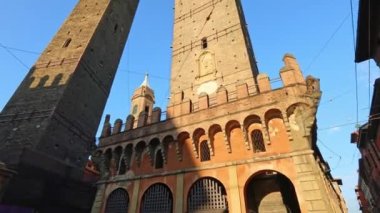 İtalya 'nın mavi gökyüzündeki şehrin sembolü olan Bologna' nın İki Kulesi 'nin perspektif alt manzarası. Asinelli Kulesi ve Garisenda Kulesi tarihi şehir merkezinde. Porta Ravegnana Meydanı 'ndaki Bologna şehrinin saat kulesiyle birlikte..