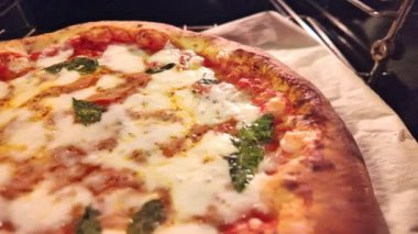 Domates, mozzarella ve fesleğen yapraklarıyla süslenmiş Margherita pizzası. Kaynayan pizza sosunun detaylı görüntüsü. Geleneksel bir İtalyan hazırlığı.