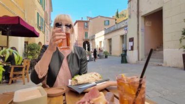 Bir turist kadın kokteyl ve tarihi bir İtalyan köyü olan Brisighella 'da Piadina Romagnola' nın tadını çıkarıyor..