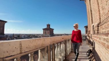 İtalya 'nın Ferrara kalesini ziyaret eden turist kadın. Etrafı su dolu geniş hendekle çevrili. Bu da ona izolasyon ve koruma hissi veriyor. Kalenin kare şeklinde 4 büyük kulesi var..