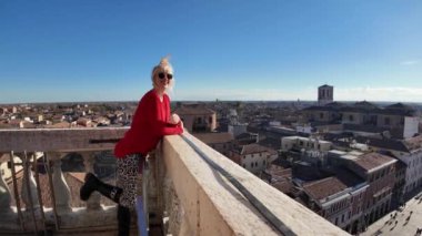 Ferrara Kalesi 'ni ziyaret eden turist kadın, Aslanlar Kulesi' nin sarmal merdivenlerine tırmandı ve Estense Kalesi 'nin tepesine ulaştı. Kırmızı çatıları ve antik kiliseleriyle şehrin çarpıcı manzarasına baktı..