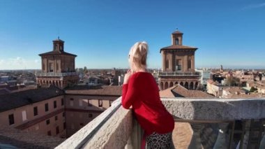 İtalya 'nın Ferrara kalesini ziyaret eden turist kadın. Etrafı su dolu geniş hendekle çevrili. Bu da ona izolasyon ve koruma hissi veriyor. Kalenin kare şeklinde 4 büyük kulesi var..