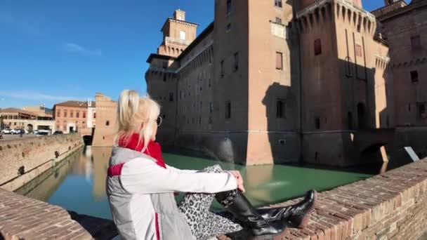 イタリアのフェラーラ城を訪れる観光客 水で満たされた広い堀に囲まれて それは孤立と保護の感覚を与えます 城は4つの巨大な塔が付いている正方形を備えています — ストック動画