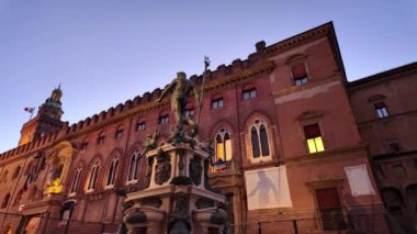 Bologna 'daki aydınlanmış Accursio Sarayı' ndaki Neptün heykeli. Piazza Maggiore Meydanı 'nda, tarihi ve sanatsal ihtişam İtalyan bayrağıyla güzellikle vurgulanırken, hayat doludur.