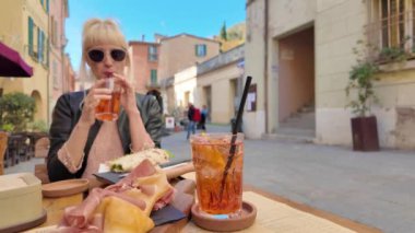 İtalya 'nın Emilia-Romagna bölgesindeki Brisighella tarihi köyünde kokteyl içen turist kadın. Çiğ jambon ve kreşenli Romagna piadina tabanlı Aperitif..