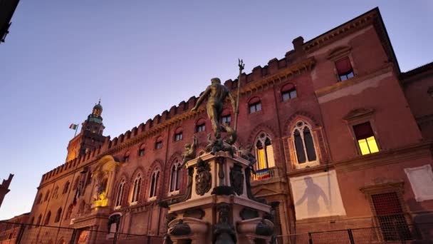 夜のクロークの下で ボローニャのネプチューン像は イタリアの旗で照らされたアキュシオ宮殿の背景に押しつぶされたシルエットを鋳造し 雄大に立っています — ストック動画
