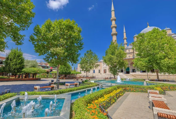 Mısır Çarşısı çeşmesi olan bir parkın sükunetinden, İstanbul 'un Yeni Camii ortaya çıkar, zarif minareleri ve süslü kubbeleri açık gökyüzüne karşı resim gibi bir zıtlık yaratır..