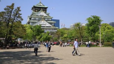 Osaka, Japonya - 30 Nisan 2017: Osaka Şatosu, Japonya 'nın görkemli bir sembolü, büyüleyici mimarisiyle ziyaretçileri büyülüyor ve kiraz çiçeklerinin resimli bir manzarasını sunuyor..