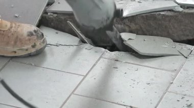 Pnömatik çekiç matkabı olan bir işçi, matkapla bir evin zeminini söküyor. Yavaşlama Hareketi