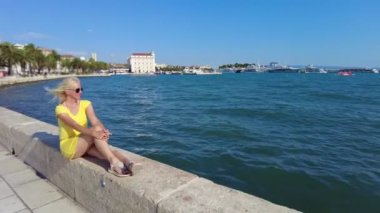 Split şehrinin rıhtımında ve ünlü feribot limanında güneşlenen bir kadın. Hırvatistan 'ın Spit kenti yazın Dalmaçya' da. Antik Roma İmparatorluğu kasabası ve Roma İmparatoru, Diocletians Sarayı.