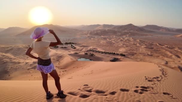 日の出にオマーンズ空の四半期の砂の上の日没の女性は 穏やかな砂漠の朝の色の鮮やかなコントラスト 黄金の砂丘の中で夜明けの光景を関連付けています — ストック動画