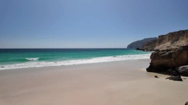 Al Fizayah Umman 'da Salalah' ın gizli plajı. Sahilde ve dağlarda otlayan develerin olduğu yerel plaj Güney Umman sahilinin bu popüler varış noktasının doğal güzelliğini artırıyor..