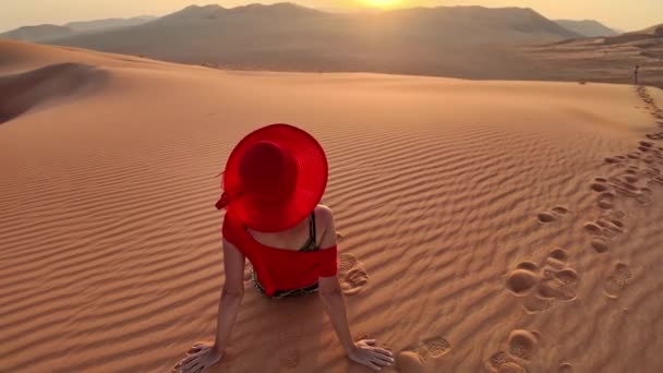 オマーン砂の上に赤く 太陽がオマーンやルーブル カリの空の四半期の砂漠の山から現れるのを目の当たりにした少女 — ストック動画