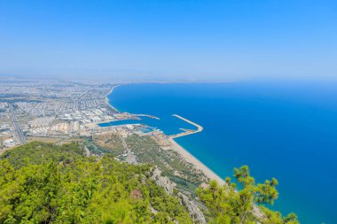 Tunektepe Kablo Arabası 'nın bakış açısından, Antalya' nın panoramik bir görüntüsü açılır. Koyu mavi kıyı şeridi sağa doğru uzanırken, şehrin yoğun mimarisi sola doğru yayılıyor..