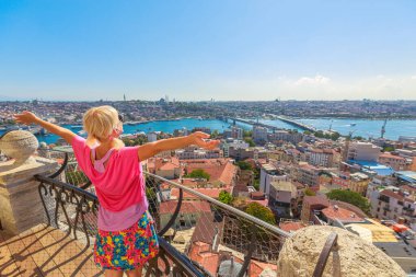 Türkiye 'de güneşli bir günde İstanbul' un yüksek perspektifinden panoramik manzarasının keyfini çıkaran açık kollu bir kadının arka görünüşü
