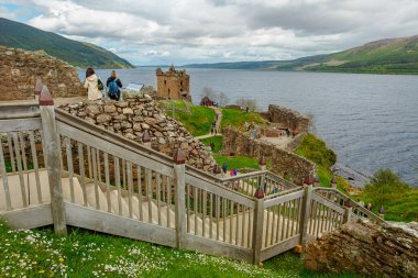 Loch Ness, Scotland, United Kingdom - May 24, 2015: tourist people on the strairway of Urquhart Castle beside Loch Ness lake. Visited for the legend of the Loch Ness monster: Nessie. clipart