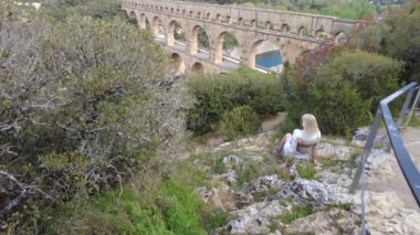 Kadın gezgin, Fransa 'daki Provence' ın sakin manzarasında UNESCO dünya mirası Pont du Gard 'a bakıyor..