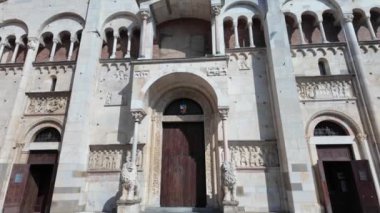 Modena Katedrali 'nin güneşli manzarası ve tarihi şehir merkezindeki girişi koruyan aslan heykelleri.