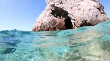 İtalya 'daki Toskan Takımadaları' nın Elba Adası 'ndaki Sansone Sahili' nin berrak mavi sularında yüzen bir paspasın üzerinde uzanan genç bir kadının çift katlı görüntüsü..