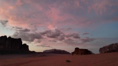 Nefes kesen günbatımı Jabal Al Qattar uçurumunun üzerinde gökyüzünü boyar, Ürdün 'ün görkemli Wadi Rum çölündeki Bilgelik Sütunları' nın simgesiyle birlikte.