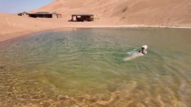 Boş Bölge Çölü 'nde termal havuzun keyfini çıkaran bir turist kadın. Rub al Khali çöl termal havuzu volkanik bölgelerde jeotermal enerji tarafından ısıtılan doğal sıcak su kaynakları