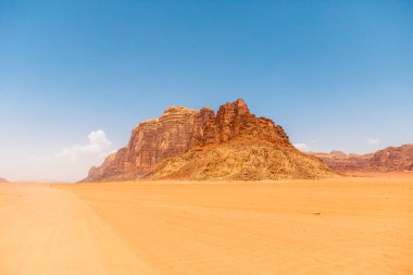 Wadi Rum 'un dramatik manzaralarının nefes kesen görüntüsü, yüksek uçurumlar ve geniş kırmızı kumlar Ürdün' ün ikonik çöl çöllerinde açık mavi gökyüzüne karşı sergileniyor.