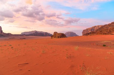 Nefes kesen günbatımı Jabal Al Qattar uçurumunun üzerinde gökyüzünü boyar, Ürdün 'ün görkemli Wadi Rum çölündeki Bilgelik Sütunları' nın simgesiyle birlikte.