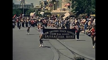 Orlando, Bay Lake, Florida, ABD - 1979 civarı: Kırmızı ve beyaz üniforma giyen bando 1979 yılında Magic Kingdom lunaparkında izleyicilerle dolu bir sokakta yürüyor
