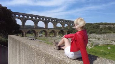 Gezgin kadın Fransa 'nın Provence kentindeki tarihi Pont du Gard su kemeri manzarasının keyfini çıkarıyor.