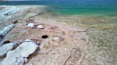 Ürdün kurak arazisine karşı Ölü Deniz 'in eşsiz mineralzengin sularını ve tuz oluşumlarını gösteren sakin bir manzara.