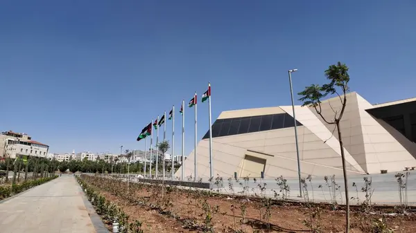 stock image Royal Tank Museum, Amman, Jordan - May 4, 2024: View of the Royal Tank Museum entrance in Jordan, showcasing flags and modern architecture under a bright blue sky