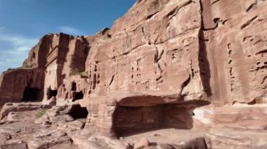 Turist, Ürdün 'ün Ürdün kentindeki Petra kentindeki antik oymalarla kumtaşı kayalıklarındaki inanılmaz Kraliyet Mezarları' nın fotoğrafını çekiyor.