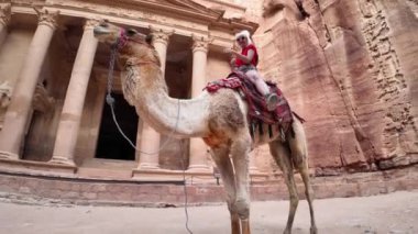 Turist, Ürdün 'deki bir unesko dünya mirası sahası olan Petra' daki Hazine 'nin önündeki deve yolculuğunun tadını çıkarıyor.