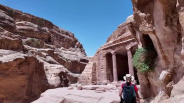 Sırt çantası takan turist Ürdün 'deki Petra antik kentini keşfediyor. Ürdün' deki karmaşık kaya kesimi mimarisine hayret ediyor.