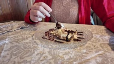 Çikolata ile pasta tatlısı yiyen bir kadının yakın plan çekimi. Çikolata serpiştirilmiş cazip bir dilim pasta, İtalya 'da bir restoranda bir kaşıkla tadını çıkarıyor.