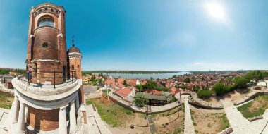 Drone view of a woman is standing on a platform of the Belgrade tower, admiring the panoramic view of Belgrade, Serbia, with the danube river flowing through the city clipart