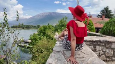 Kırmızı şapkalı ve üstü açık turist, Makedonya 'nın kuzeyindeki Ohri Gölü' ndeki Kara Drin pınarlarının keyfini çıkarıyor.