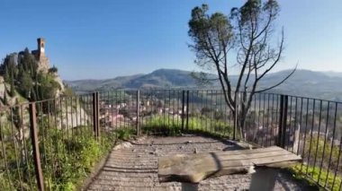 Brisight köyüne bakan ahşap bank, Saat Kulesi Torre dellOrologio, Kuzu Vadisi ve açık mavi gökyüzü altında İtalyan apenatifleri.