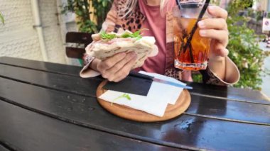 Turist kadın elinde piadina romagnola ve spritz kokteyli tutuyor. Brisighella, İtalya 'da bir restoranda ahşap bir masada oturmuş geleneksel İtalyan yemeğinin tadını çıkarıyor.