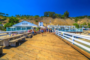 Malibu, California, United States - August 7, 2018: Malibu Farm Restaurant and Santa Monica Mountains in historic Malibu wooden Pier. Summer day in blue sky. Copy space. Popular travel destination. clipart