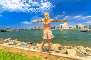 Mutlu kaygısız kadın, San Diego şehir merkezinde gökdelenleri olan Coronado Adası 'ndan ABD' nin başkenti Kaliforniya 'nın gökdelenleriyle eğleniyor. Yaz tatilinde turist. San Diego Körfezi 'nin rıhtım kenti.