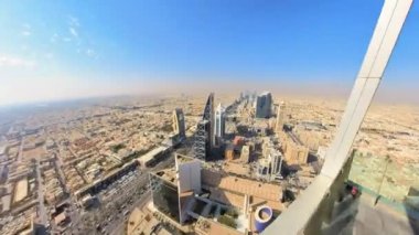 Riyad, Suudi Arabistan 'ın panoramik manzarası geniş şehir genişliğini, hareketli caddeleri ve modern mimariyi parlak, güneşli bir gökyüzü altında sergiliyor.