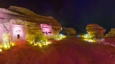 El-Ula, Suudi Arabistan 'daki Hegra arkeolojik sahasında geceleri kumtaşı uçurumlarına oyulmuş aydınlanmış Nabataean mezarları. Madain Saleh mezarlığında antik mimari ve kültür mirasının altını çizmek.