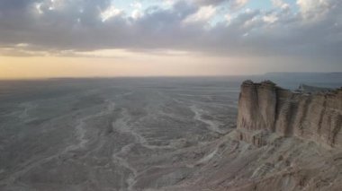 Suudi Arabistan, Riyad yakınlarındaki Jebel Fihrayn 'daki dramatik kaya oluşumları, geniş çöl manzarası üzerinde nefes kesici bir günbatımı manzarası yaratıyor, engebeli arazide uzun gölgeler bırakıyor.