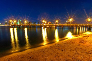 Eski ahşap iskele, San Diego Körfezi sahiline yansıyor. Coronado feribotu Coronado Adası, Kaliforniya, ABD 'ye iniyor. Arka planda San Diego şehir merkezi var. Gece manzaralı şehir manzarası.